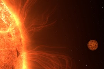 A close-up of a star dominates the left side of the image. Its surface glows intensely in various shades of orange, showing irregular structures like darker spots. Delicate, glowing plasma filaments arc outward from the Sun's surface. On the right side of the image, a small rocky planet is visible, its reddish-brown surface marked with dark, mottled patterns. The background is black, dotted with a few white star-like points.