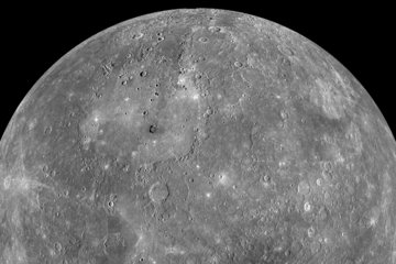 A partial black-and-white mosaic of the planet Mercury against a black background, captured by the Messenger spacecraft. The grey, spherical surface is heavily cratered, with impact sites of varying sizes, indicating billions of years of cosmic bombardment. The surface material is dark and basaltic, with prominent bright streaks (rays) emanating from younger craters where fresh subsurface material was ejected. The absence of atmospheric blurring produces sharp, high-contrast features, indicating a world directly exposed to the space environment and solar radiation.
