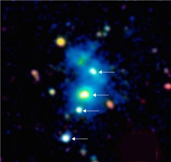 Image of the region of the space occupied by the rare quasar quartet. The four quasars are indicated by arrows. The quasars are embedded in a giant nebula of cool dense gas visible in the image as a blue haze. The nebula has an extent of one million light-years across, and these objects are so distant that their light has taken nearly 10 billion years to reach telescopes on Earth. This false color image is based on observations with the Keck 10m telescope on the summit of Maunakea in Hawaii. Image of the region of the space occupied by the rare quasar quartet. The four quasars are indicated by arrows. The quasars are embedded in a giant nebula of cool dense gas visible in the image as a blue haze. The nebula has an extent of one million light-years across, and these objects are so distant that their light has taken nearly 10 billion years to reach telescopes on Earth. This false color image is based on observations with the Keck 10m telescope on the summit of Maunakea in Hawaii.