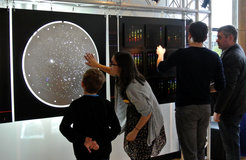 Photo of an art exhibit by SDSS Artist-in-Residence Tim Fitzpatrick in St Andrews, Scotland, on 7 November 2015. Volunteers and visitors examine a backlit SDSS plate on the left and art inspired by astronomical spectra on the right.